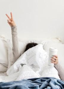 woman in bed covering face with blanket